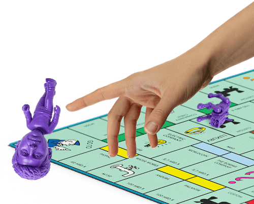 Eine Hand schnippt eine Spielfigur von einem Spielbrett.