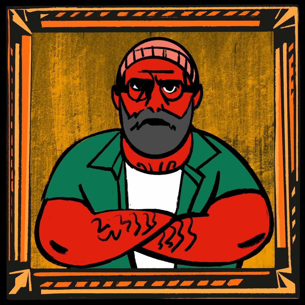 Ein bärtiger Mann mit Brille und Mütze in einem goldenen Rahmenverschränkt die Arme