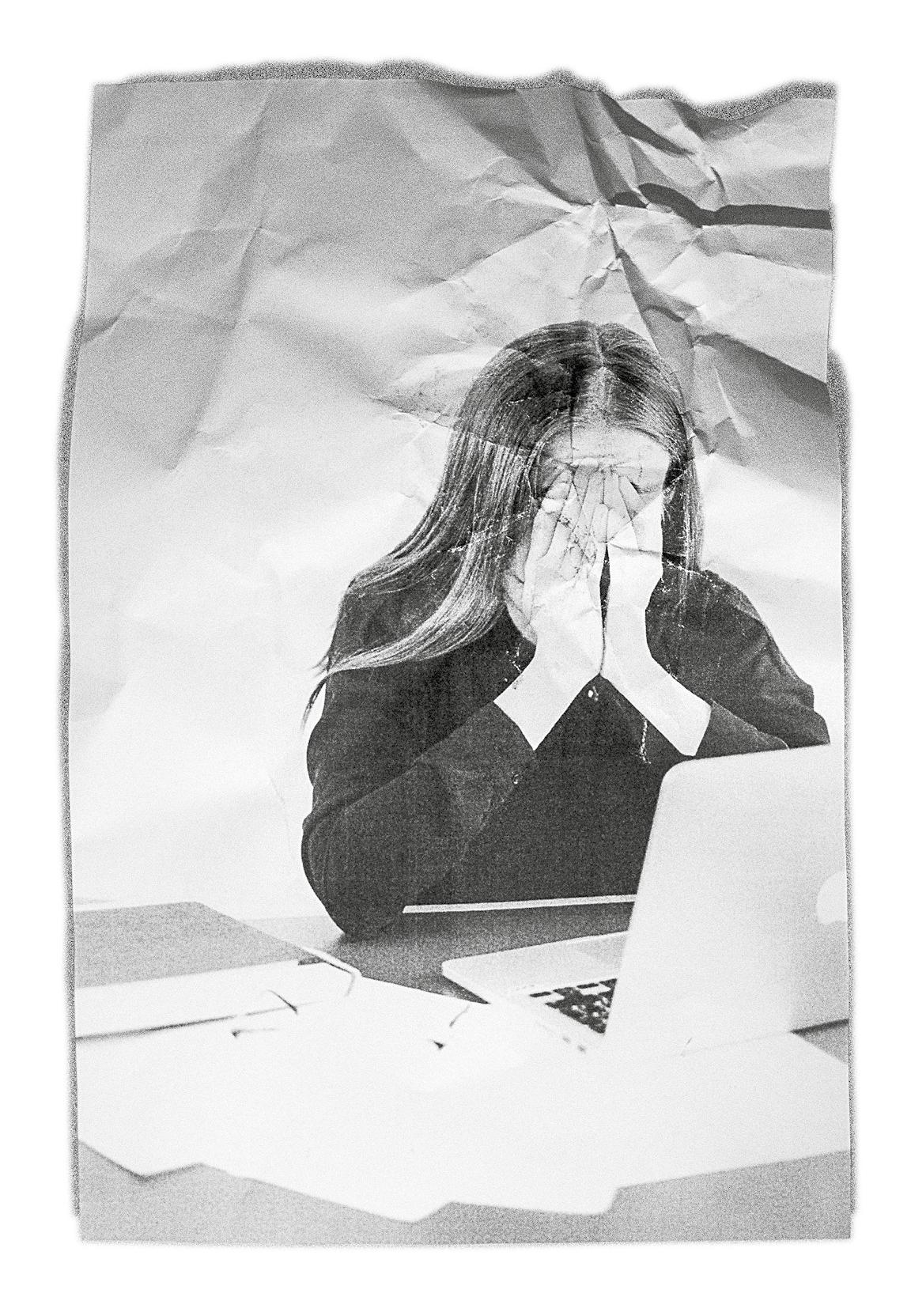 Eine Person vor einem Laptop, die beide Hände vor dem Gesicht zusammenschlägt