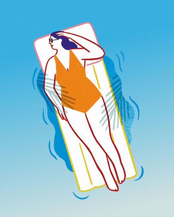 Eine Person im Badeanzug liegt auf einer Luftmatratze und schwimmt damit auf Wasser.